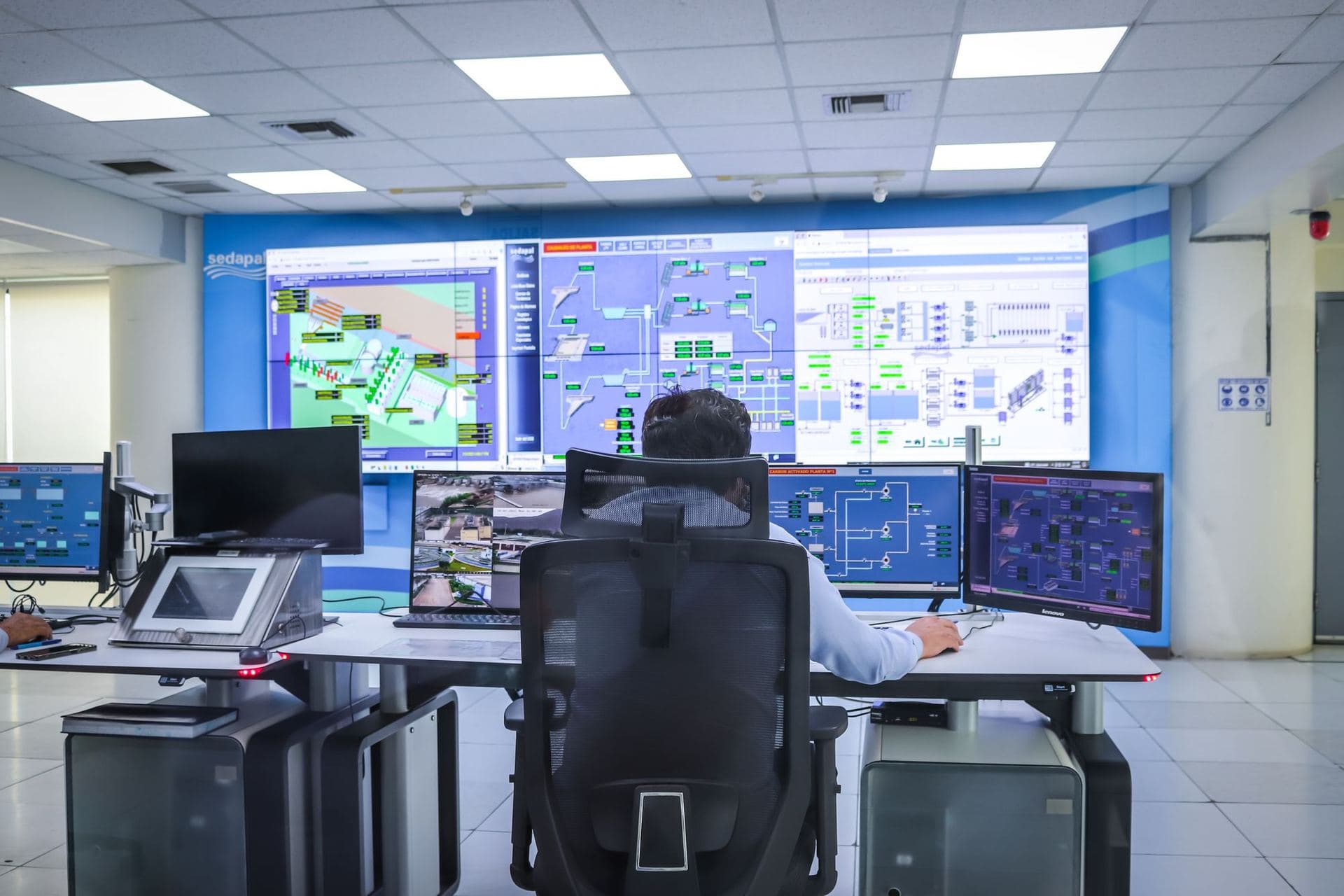 Operator watching a wall of monitoring screens in a control room